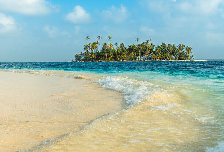 Plaża nad Oceanem Spokojnym. Mała wysepka, a wokół niej plaża i błękitna woda