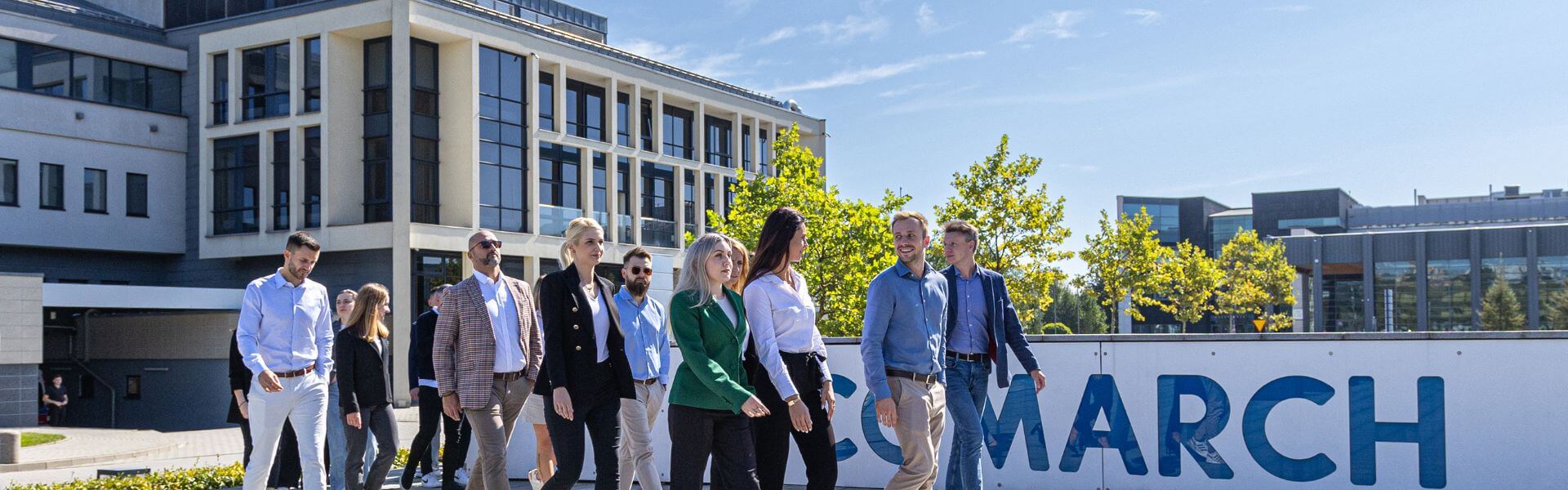 Zespół pracowników przechodzi przez krakowski kampusComarch rozmawiając