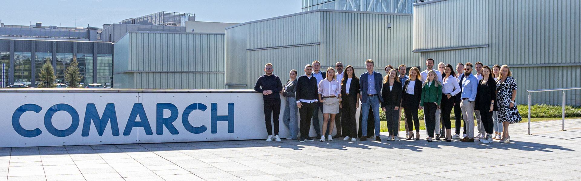 zespół pozujący do zdjęcia na tle kampusu Comarch w Krakowie