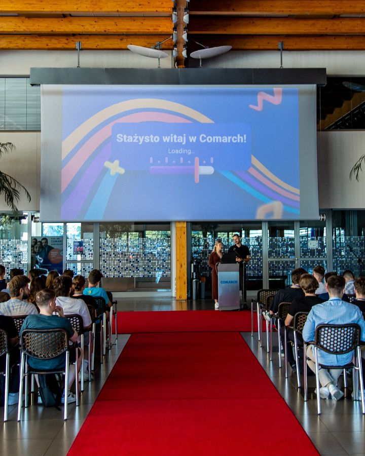 Rozpoczęcie poprzedniej edycji stażu. Powitanie wyświetlane na wielkim ekranie w sali konferencyjnej.