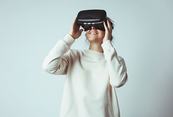 Kobieta bawi się założonymi na głowie okularami VR. Tak wygląda projektowanie interfejsu użytkownika