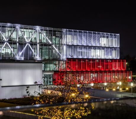 Zdjęcie przedstawia jeden z budynków kampusu Comarch w Krakowie, podświetlony na biało-czerwono z okazji Święta Niepodległości