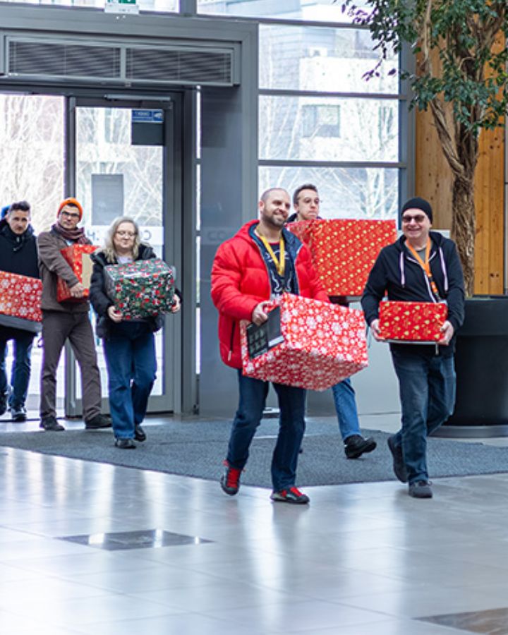 Grupa pracowników przynosi na zbiórkę zapakowane prezenty dla podopiecznych hospicjum