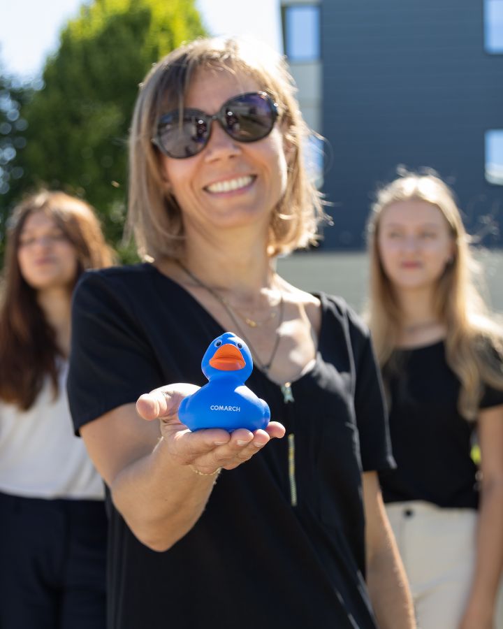 Wyciągnięta dłoń jednej z naszych koleżanek. Na niej niebieska gumowa kaczuszka z logo Comarch