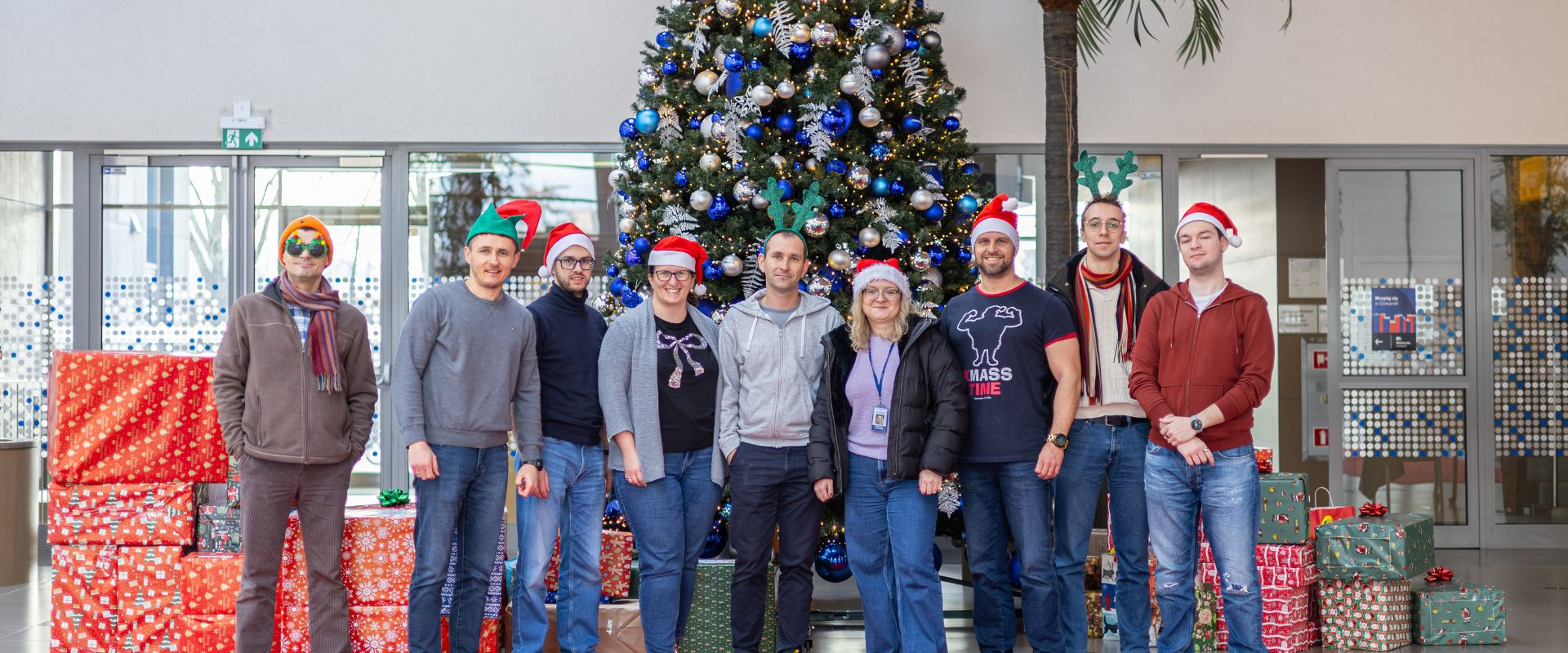 Uśmiechnięta grupa pracowników pozująca do zdjęcia w świątecznych strojach