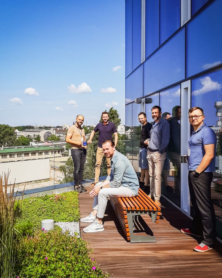 Zespół z Łodzi pozuje do zdjęcia na zielonym tarasie. W tle piekne błękitne niebo.