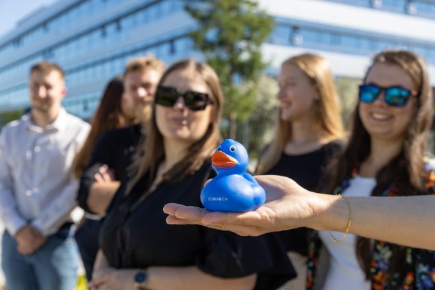 4 osoby siedzące w studio nagraniowym podcastów, uśmiechające się do fotografa