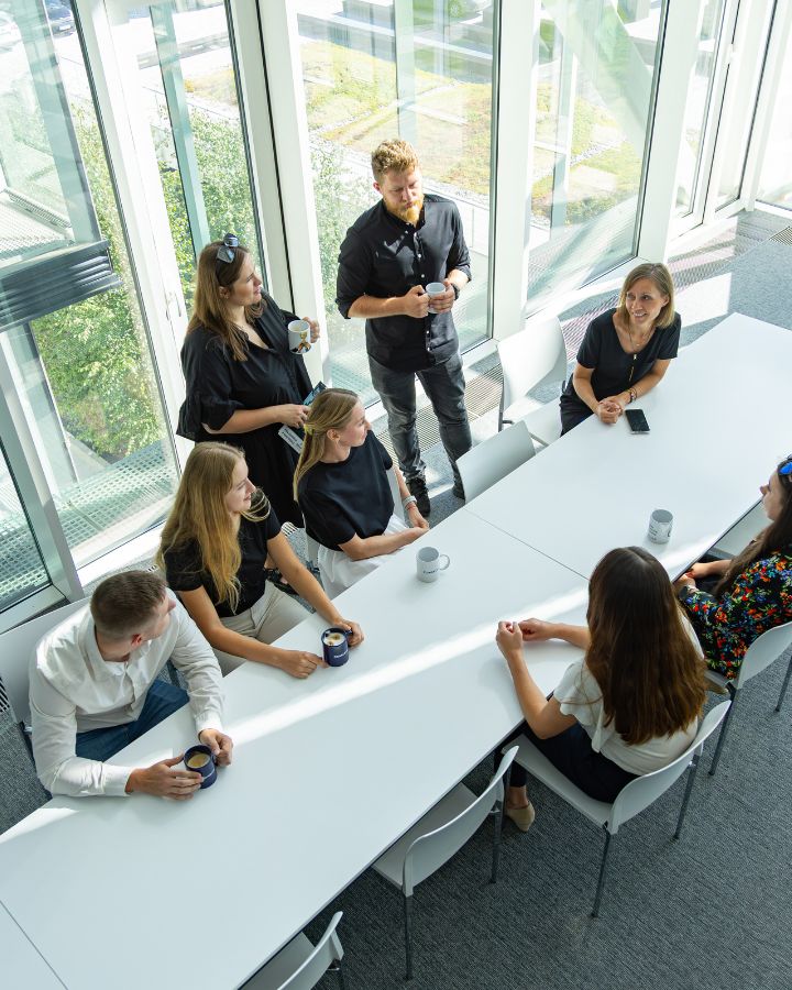 Zespół dyskutujący przy dużym stole w budynku SSE6 w Krakowie. Widok z góry