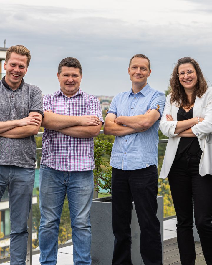 Grupa pracowników pozująca do zdjęcia na tarasie w lubelskim oddziale. Wszyscy w tej samej pozycji z założonymi rękami, z czego właśnie się śmieją