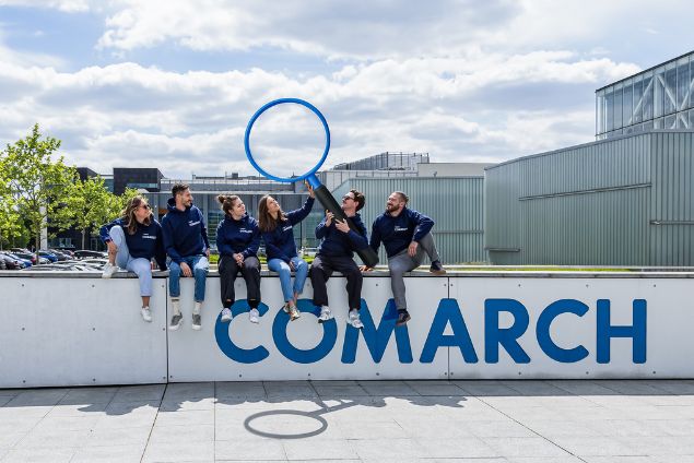Zespół Employer Branding siedzący na terenie kampusu Comarch, trzymający wielką lupę